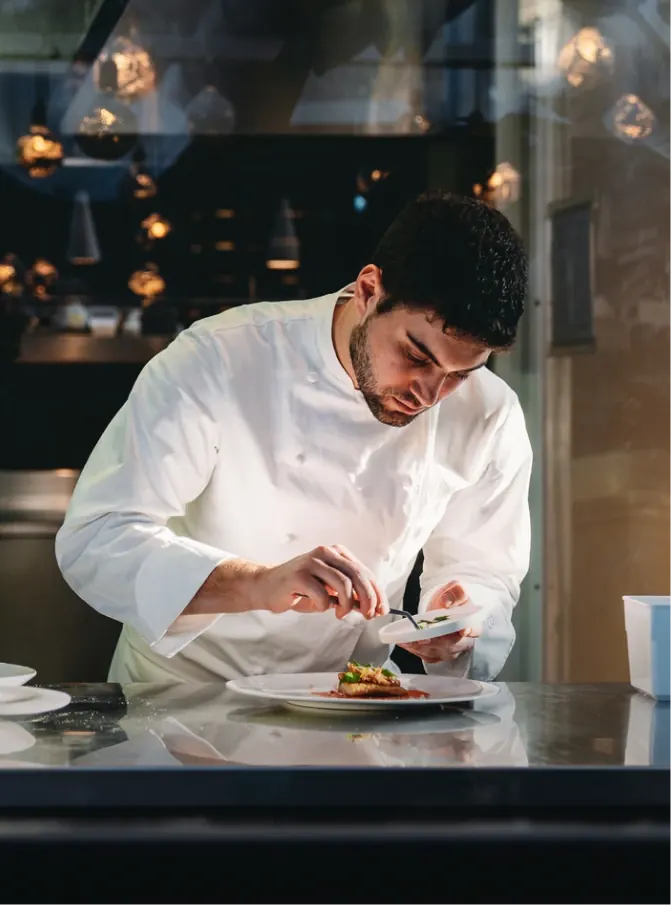 Chef in whites plating a dish in a restaurant kitchen