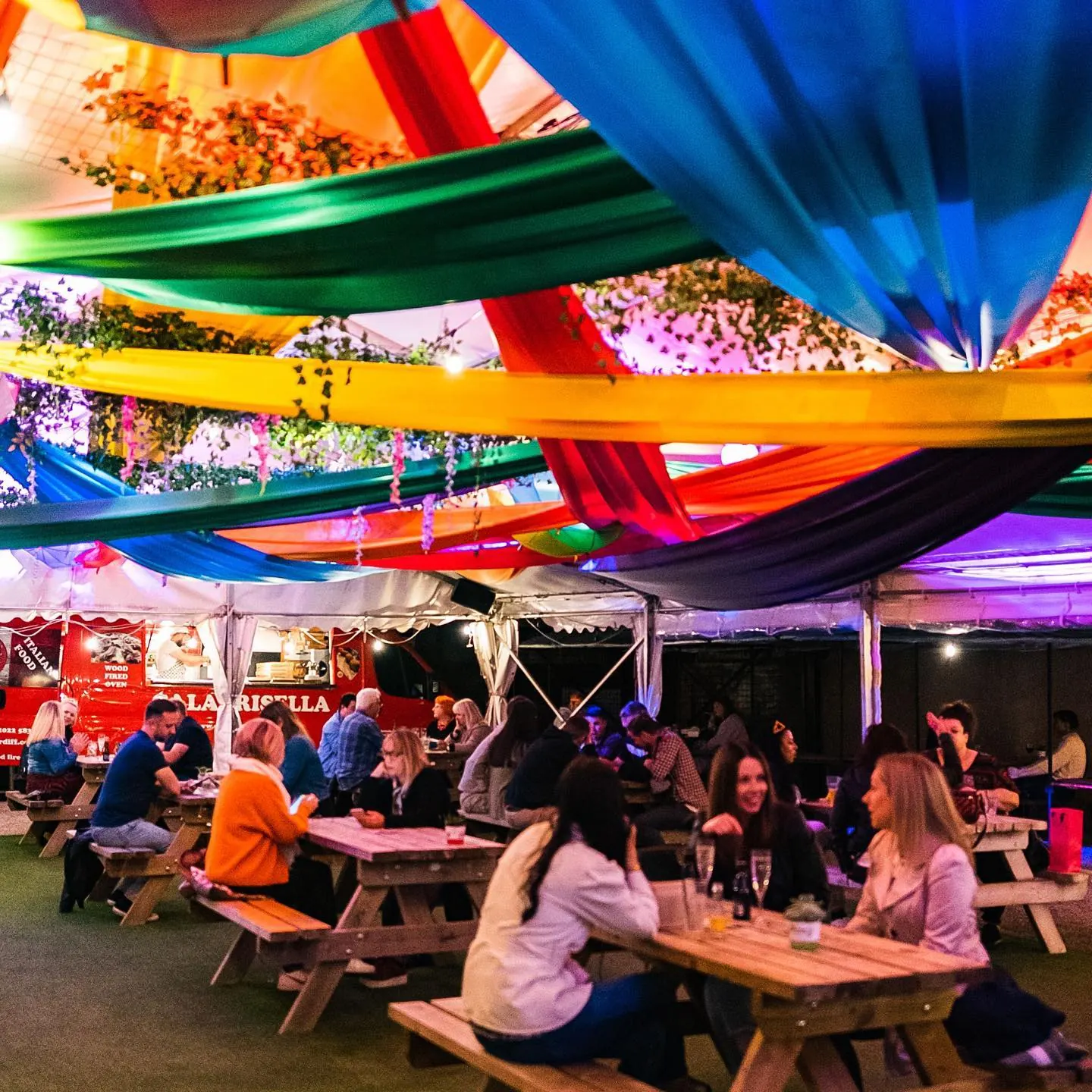 Colourful draped marquee over picnic benches with guests