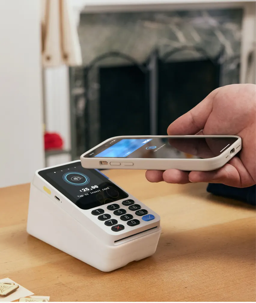 Mobile phone in hand to make a payment using a white PayPal Reader