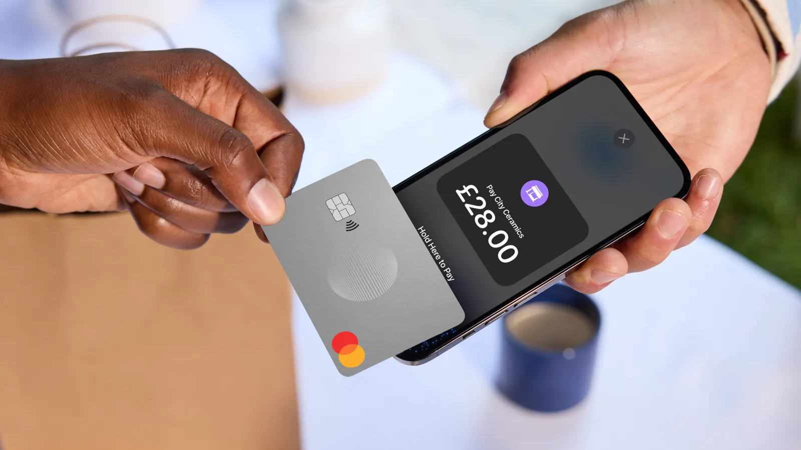 A hand holding a card to pay using the Tap to Pay feature on the phone.